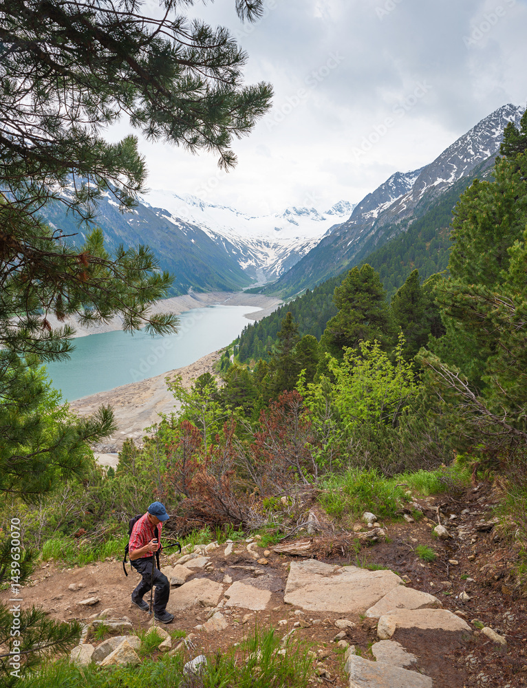 man hiking upwards at trail above Schlegeisspeicher accumulation lake to Olperer hut.