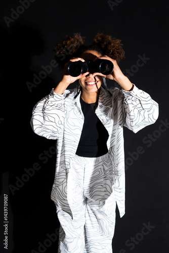 Fashionable woman holding binocular against black background