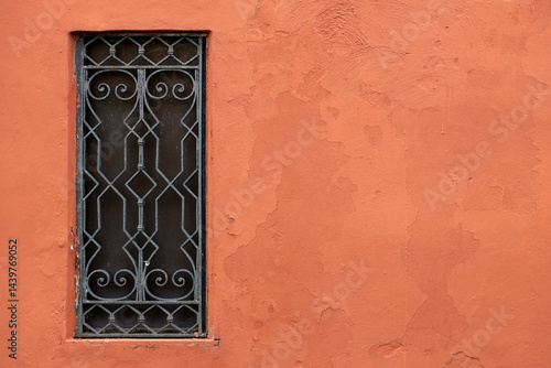 Decorative iron window on terracotta wall