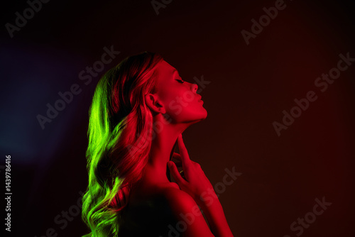Elegant young woman with blond hair in neon red and green lighting, showcasing beauty and fashion style