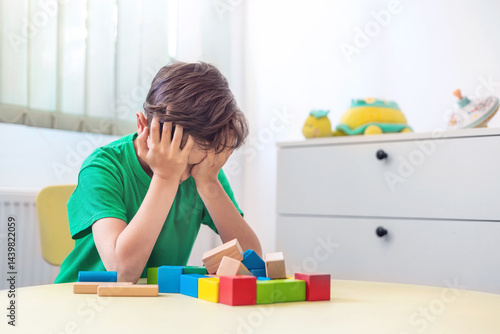 Canvastavla Tired little boy covering face with hands after playing with wooden blocks, expe