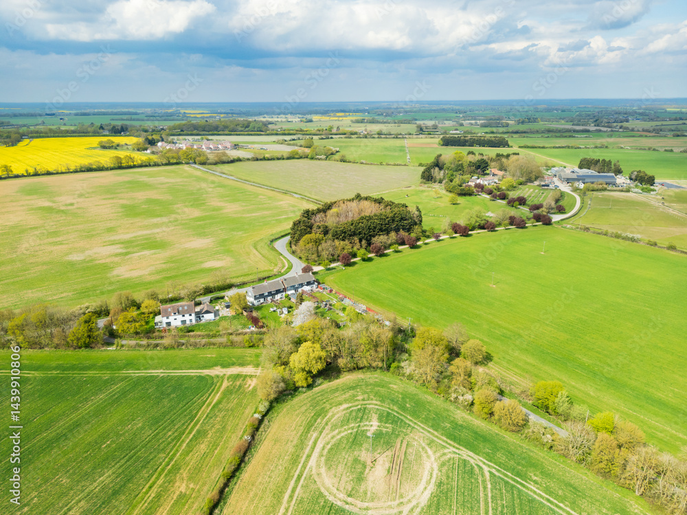 Aerial view of a small English hamlet showing a small number of terraced houses surrounded by prime agricultural land in Britain.