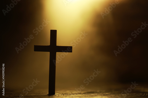 Obraz na płótnie Silhouette of a Wooden Cross with Warm Light in Background Symbolizing Faith and