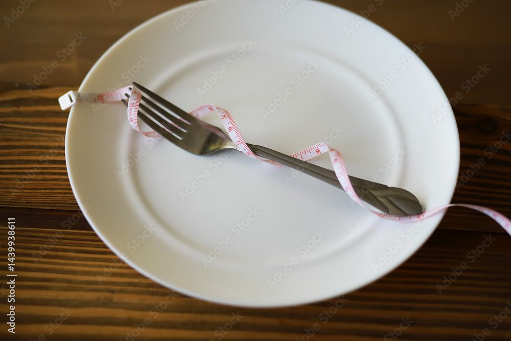Empty White Plate with Fork Wrapped in Measuring Tape Symbolizing Diet and Weight Loss