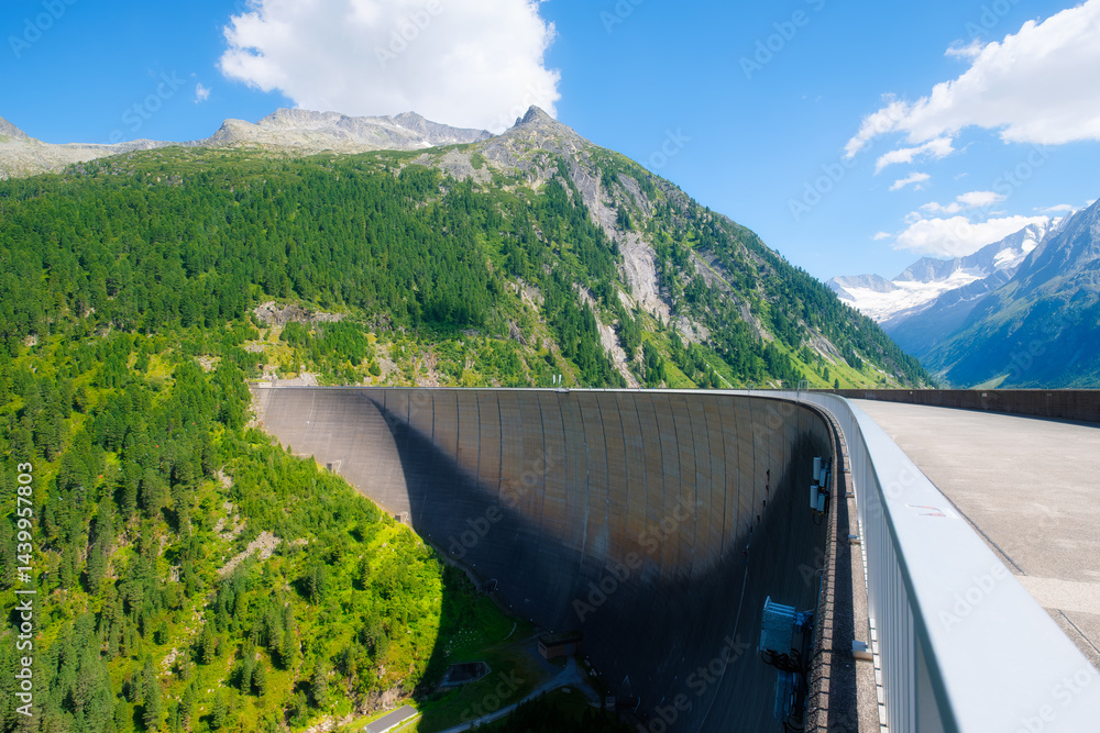 Dam and high mountain range in Austria. Mountain landscapes during summer. Warm sunny weather and clear skies. Place for mountain hiking, travel and vacation. Wallpaper, postcard, photo.