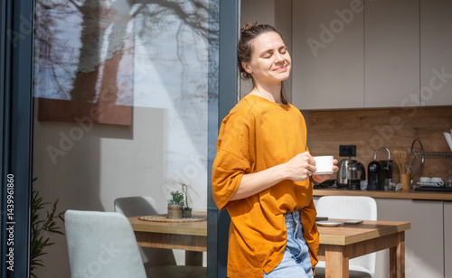 Obraz na płótnie Young cheerful woman enjoying morning sun and cup of coffee on terrace of house w salonie