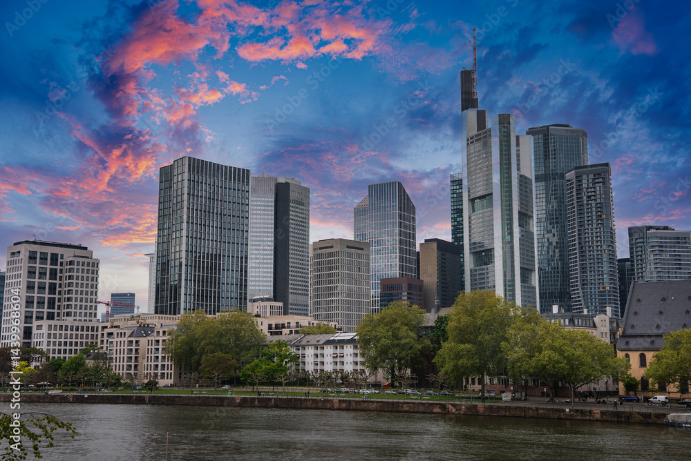 Modern skyline of Frankfurt, Germany, featuring the Commerzbank Tower, tree lined waterfront, and a mix of contemporary and historic architecture.