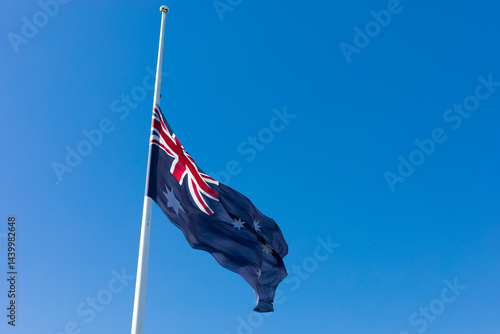 Australian Flag flown at half mast on a clear day with blue sky