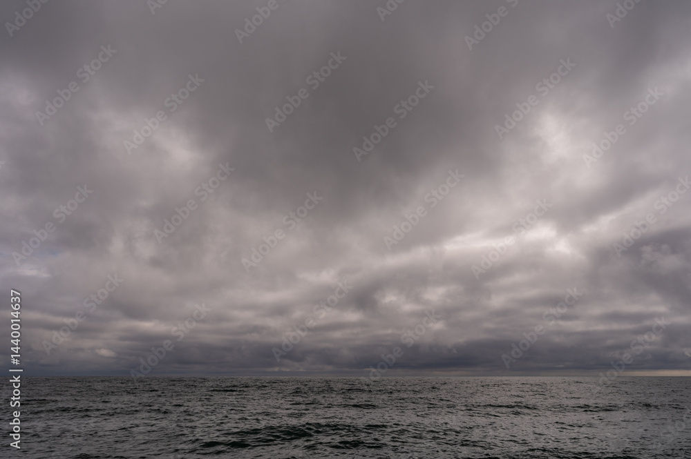 Dark storm clouds over ocean. Dramatic seascape. Clouds and rain flurry over sea.