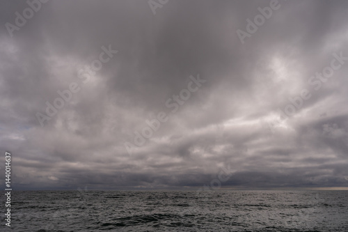 Obraz na płótnie Dark storm clouds over ocean. Dramatic seascape. Clouds and rain flurry over sea. w salonie