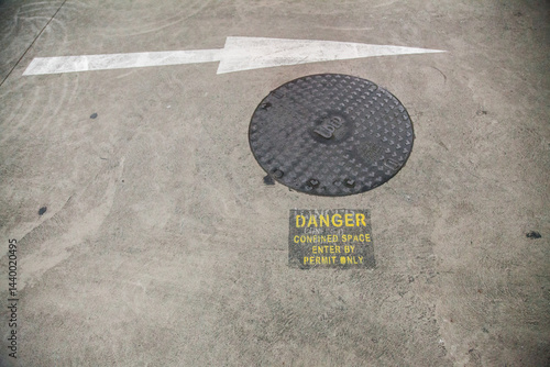Danger confined space enter by permit only sign in car park beside man hole
