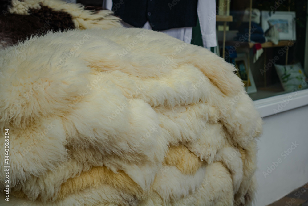 A stack of white sheepskins in front of a shop window A stack of white sheepskins in front of a shop window