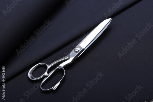 Obraz na plátne Professional sewing scissors rest atop a bolt of deep blue denim fabric, representing craftsmanship, fashion tailoring, and precision in garment-making
