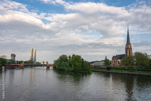 Obraz na płótnie Frankfurt's Main River flows past the Dreikonigskirche spire, a historic stone bridge, and the modern ECB tower under a partly cloudy sky. w salonie