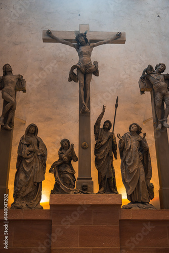 Obraz na płótnie Detailed crucifixion sculpture with Jesus Christ, mourners, and saints in a church in Frankfurt, Germany, illuminated with a warm glow. w salonie