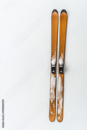 Minimalist top-down view of brown snow skis on powdery white snow with space for winter background