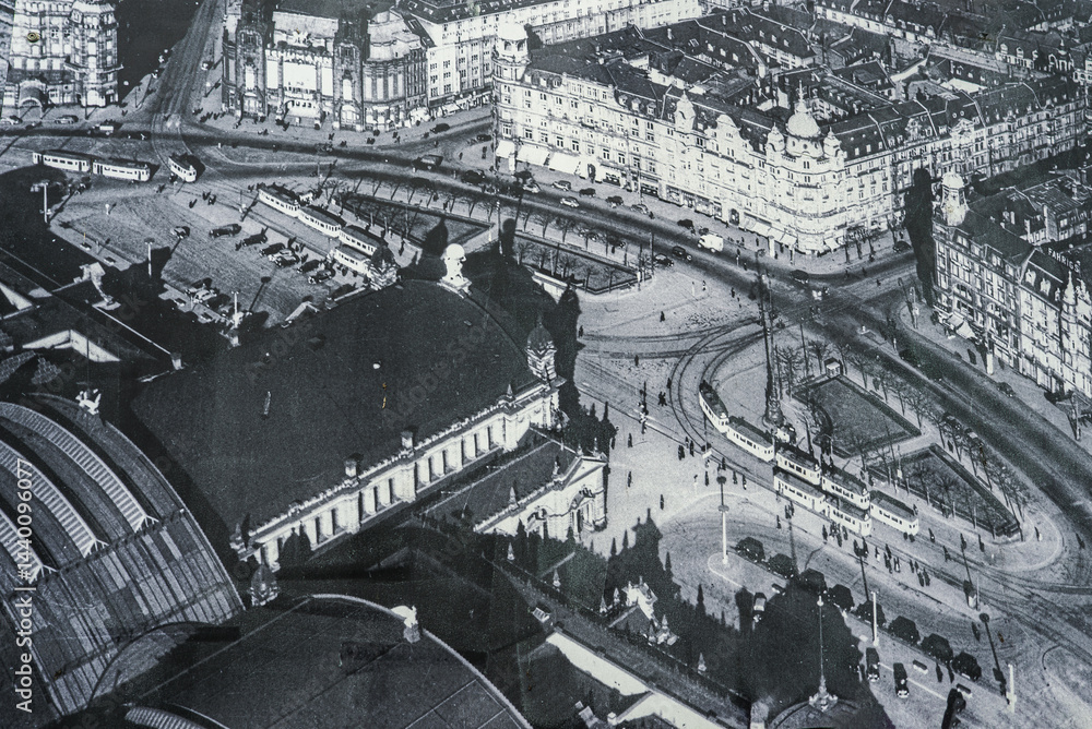 Aerial view of Frankfurt Hauptbahnhof in Germany, showcasing its arched roof, tram tracks, busy streets, and classic European style architecture.
