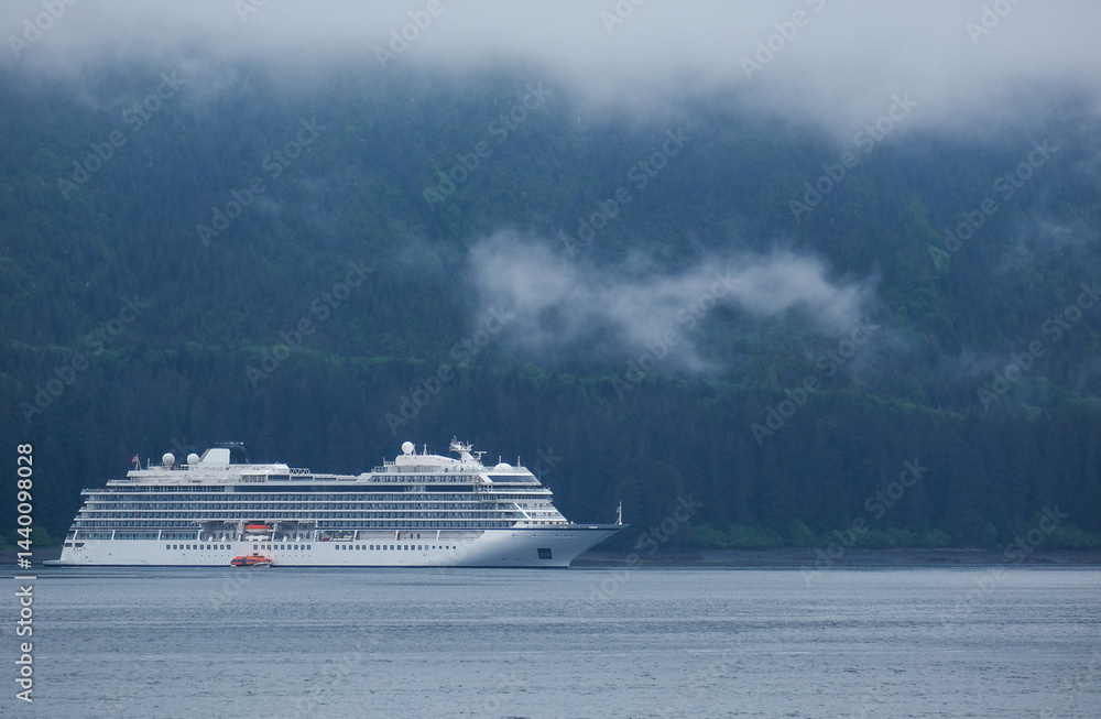 Luxury cruiseship cruise ship liner Orion and kayaks boat in Hoonah Icy Strait Point Bay, Alaska with low hanging clouds and nature landscape scenery