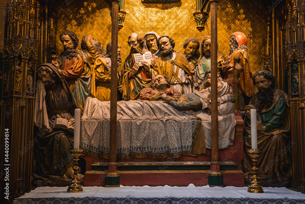 Intricate altarpiece depicting a central figure on a bed, surrounded by expressive figures, framed by ornate gold and wood in a Frankfurt cathedral.