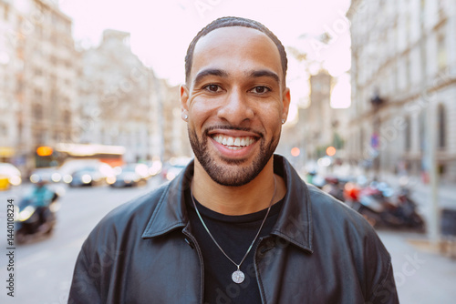 Close up portrait of a smiling multiracial young bearded tourist with braids, enjoying his trip to barcelona, looking at camera.