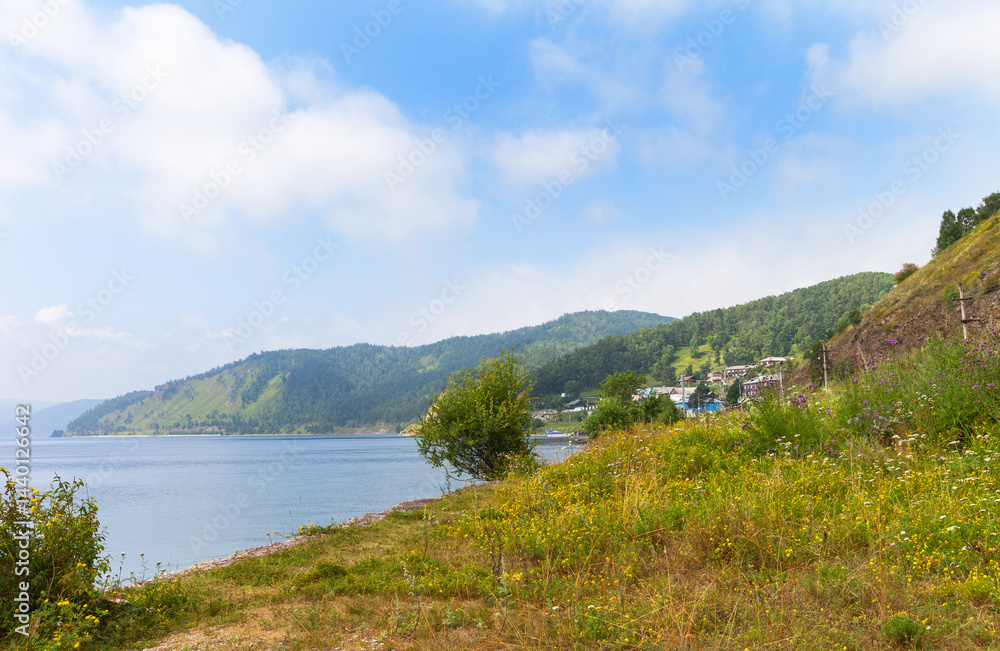 Obraz premium Beautiful landscape of coast of Baikal Lake. View of the village of Port-Baikal on the shore lake with flowers field on a sunny summer day. Circum-Baikal Railway station. Travel and outdoor recreation