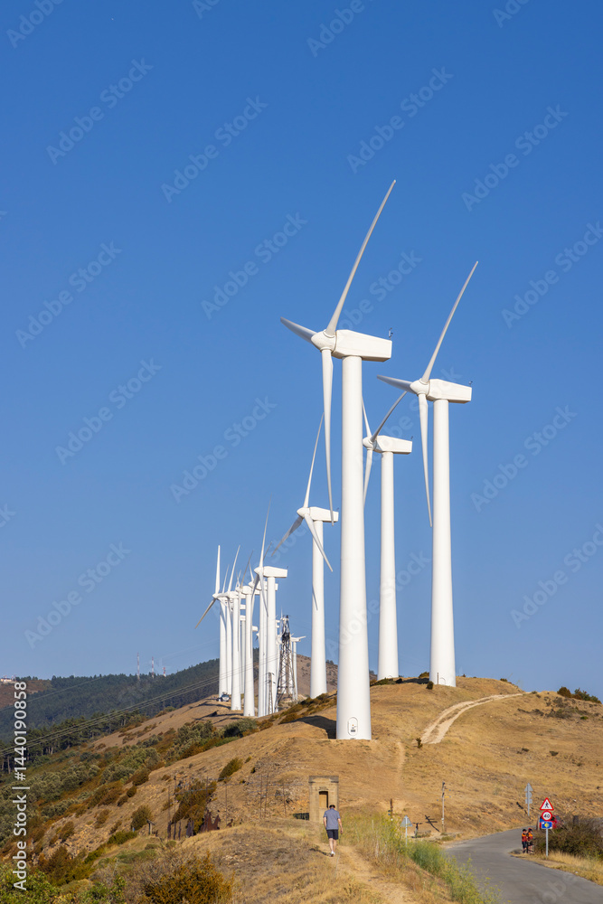 Wind turbines generating clean energy on a hilltop under a clear blue sky