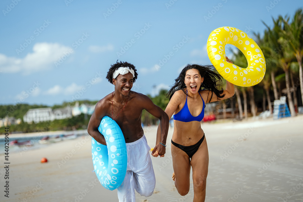 Interracial couple having fun at the beach, running through ocean waves on a tropical vacation
