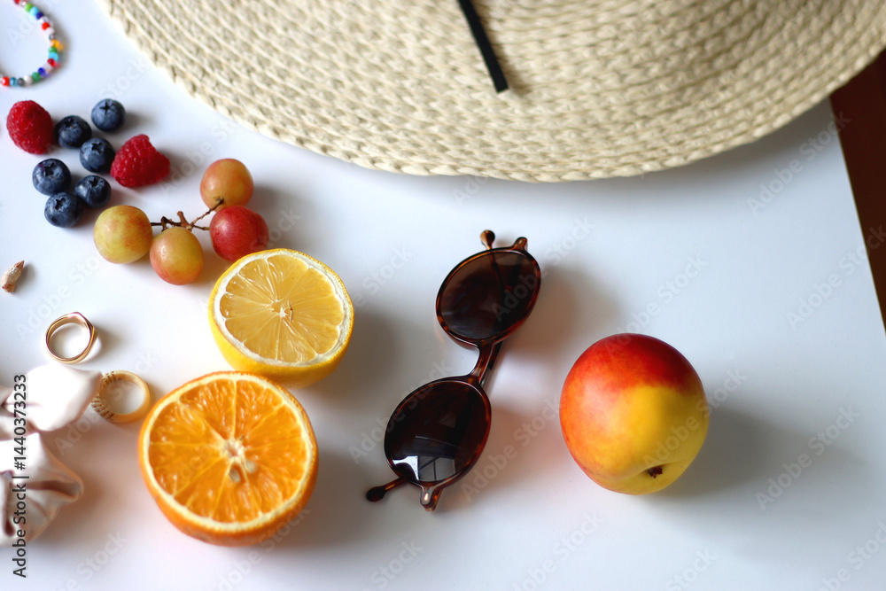 Straw hat, sunglasses, seasonal fruit, seashells and colorful accessories on white backgrounds. Cute summer essentials. Selective focus.