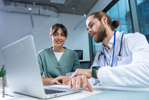 Female practitioner working with msn doctor in clinic using computer to analyze patient data