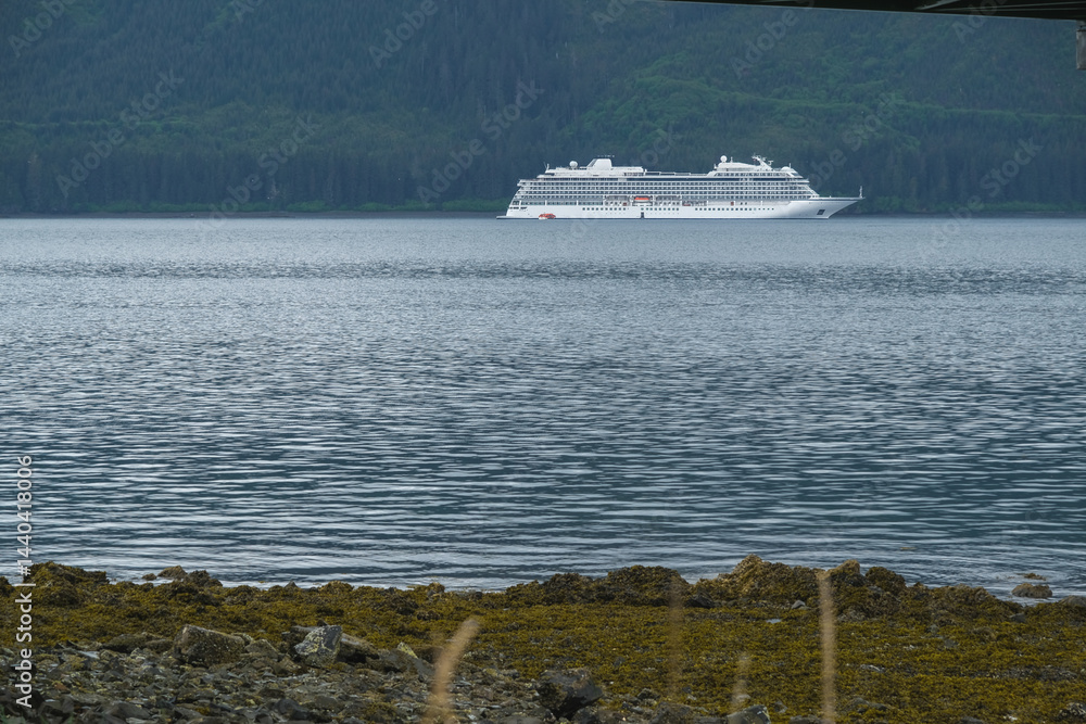 Luxury cruiseship cruise ship liner Orion and kayaks boat in Hoonah Icy Strait Point Bay, Alaska with low hanging clouds and nature landscape scenery