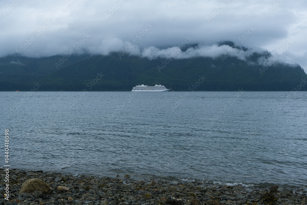 Luxury cruiseship cruise ship liner Orion and kayaks boat in Hoonah Icy Strait Point Bay, Alaska with low hanging clouds and nature landscape scenery