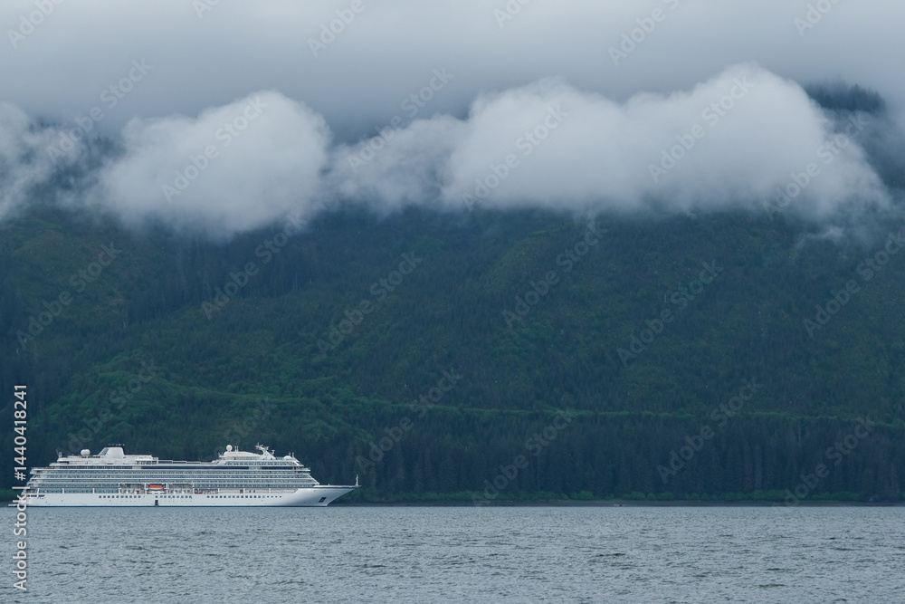 Luxury cruiseship cruise ship liner Orion and kayaks boat in Hoonah Icy Strait Point Bay, Alaska with low hanging clouds and nature landscape scenery