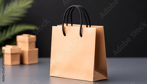 A light brown paper shopping bag with black handles sits on a gray surface, with small gift boxes softly blurred in the background