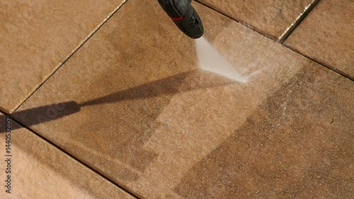 Cleaning balcony tiles with a high-pressure cleaner. Close-up