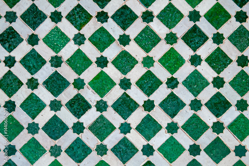 Traditional Moroccan green and white zellige mosaic with star and diamond patterns in Marrakesh, Morocco, handcrafted Islamic geometric tile artwork showcasing intricate design and cultural heritage.