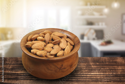 Wooden bowl full of almonds in a kitchen with blurred background