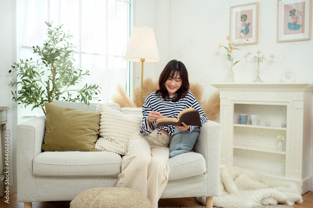 Fototapeta premium Young Woman Enjoys Reading a Book in a Cozy Living Room Setting