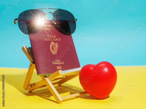Passport of Ireland with dark sunglasses in sun bed on yellow sand like surface and blue ocean background. Irish love for exotic and sunny holiday concept. Immigration to sunny places theme.