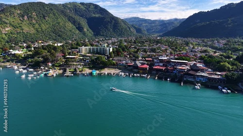 Beautiful cinematic aerial view os the Panajachel town surrounded by Toliman and Atitlan volcanoes, next to the Atitlan lake its piers and traditional fisher and tourist boats - Guatemala