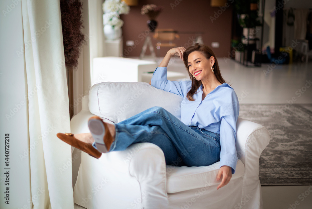 Obraz premium Beautiful woman smiling and relaxing on armchair at home