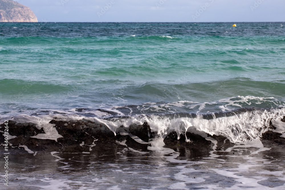 Obraz premium Mediterranean beach on the island of Majorca, or Mallorca on Balearic Sea, are part of Spain. Island in the Mediterranean Sea. Seaside vacations, clouds, seascape. View of the sea and the island. 