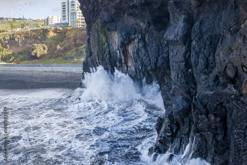 Obraz na płótnie Waves crashing against volcanic cliffs in Madeira near urban development w salonie