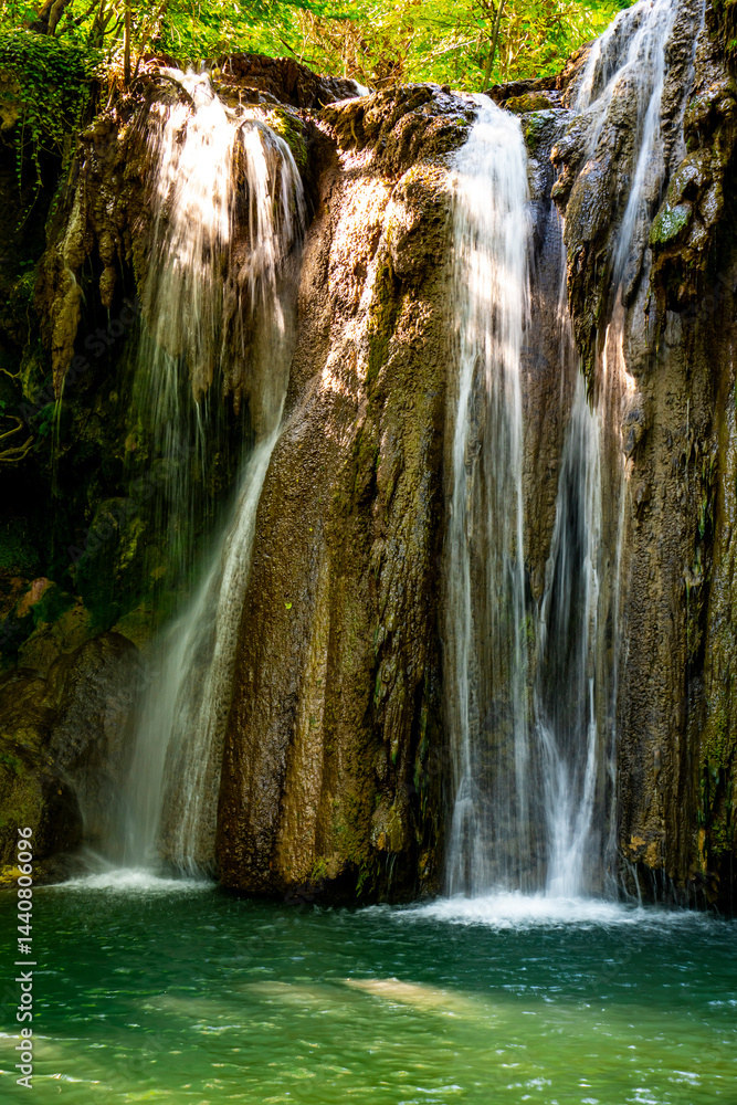 Fototapeta premium Hidden waterfall cascading through lush green forest in a serene natural oasis