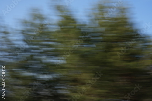 Obraz na płótnie abstract motion blur capturing the greenery of trees against a clear blue sky, creating a dynamic and artistic visual representation of speed and movement in nature, swirl, harmonious, canvas w salonie