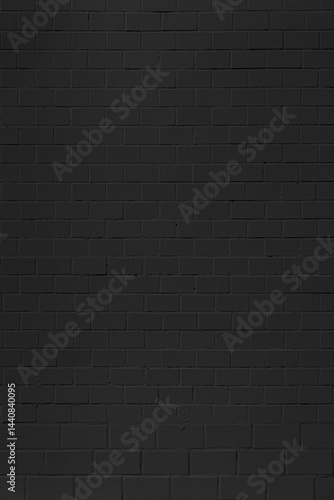 A wall made of black bricks. The wall is very plain and has no decorations. The bricks are all the same size and shape.