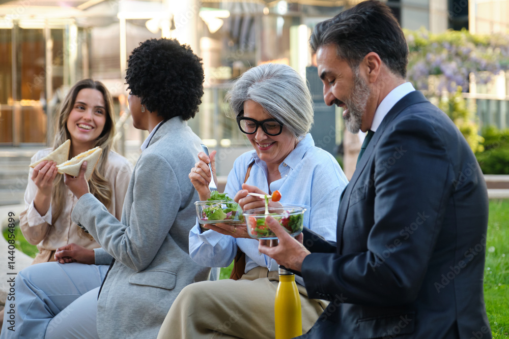 Group of multi ethnic businesspeople enjoying healthy salads and sandwiches during their lunch break outdoors