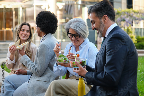 Group of multi ethnic businesspeople enjoying healthy salads and sandwiches during their lunch break outdoors