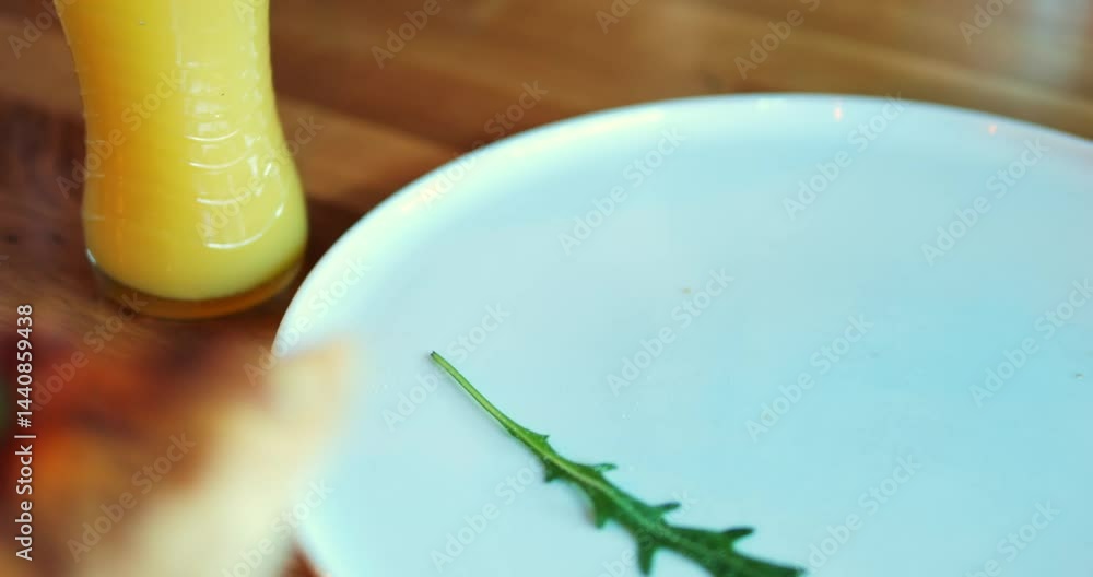 Customer picks up piece of flatbread with cherry tomatoes and arugula starting lunch at cafe. Client satisfies hunger with pizza sitting at table in pizzeria
