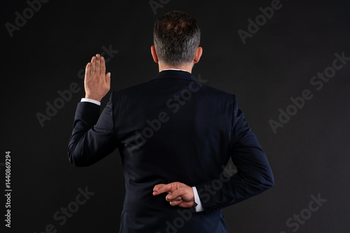 Fotografie Businessman faking an oath with fingers crossed behind back.