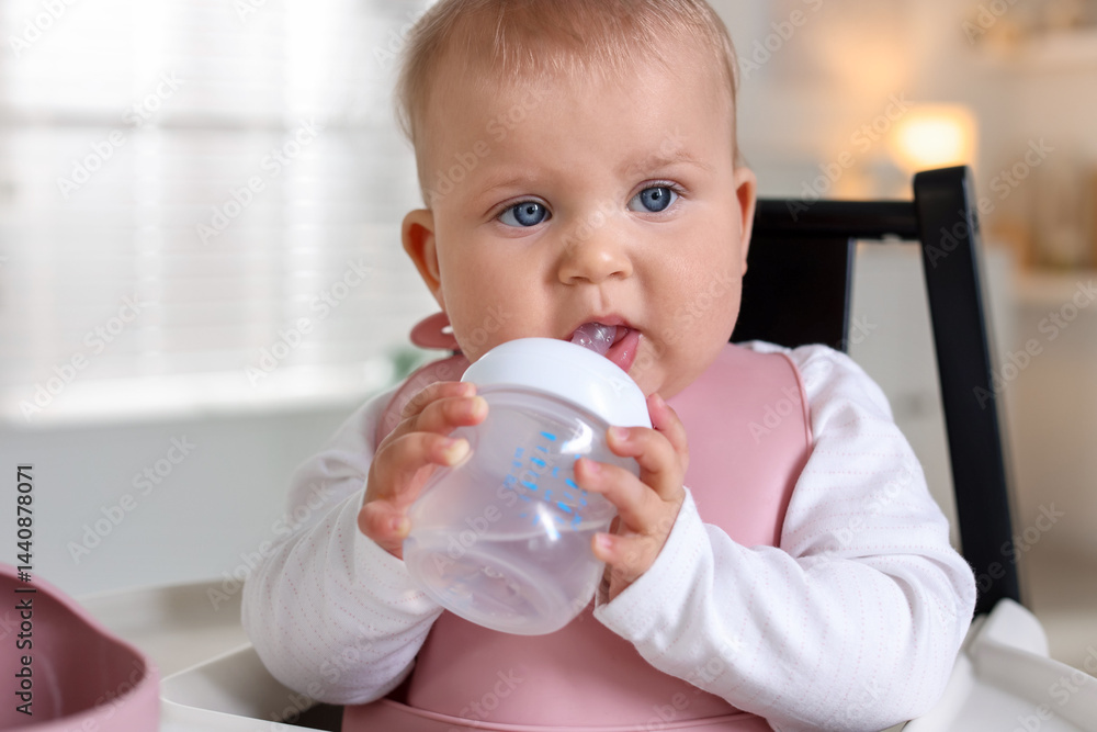 Cute little baby with bottle on feeding chair at home Cute little baby with bottle on feeding chair at home
